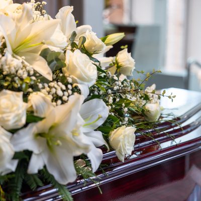 Close up of a Rosewood coffin with a floral arrangement on top