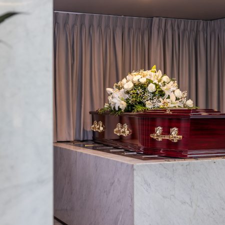 Rosewood coffin with a floral arrangement in a chapel